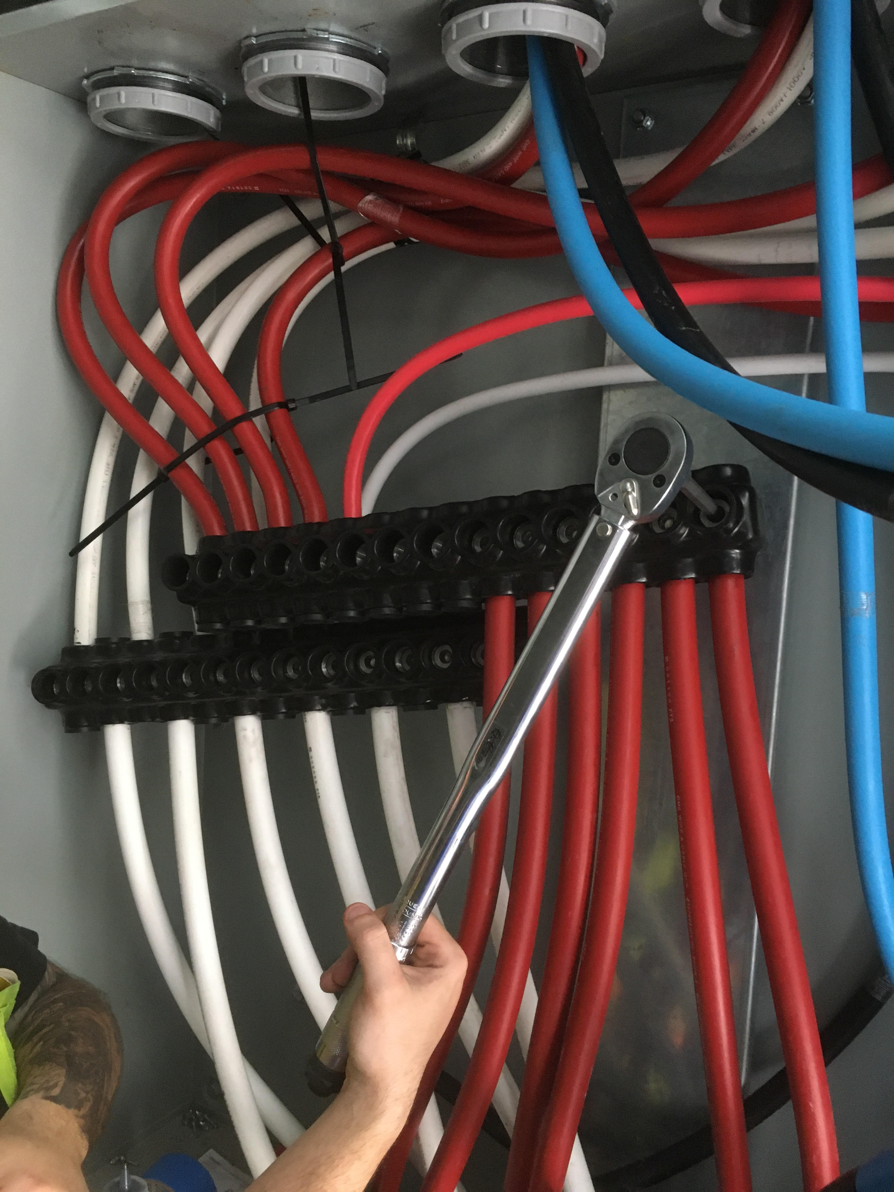 Electrician using torque wrench on bus bar connections for commercial panel in Austin TX